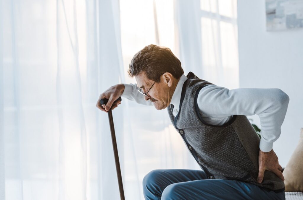 Man with a walking stick is hesitating to stand up