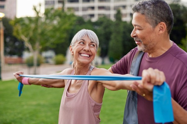 Older male and female doing light band exercise in the park